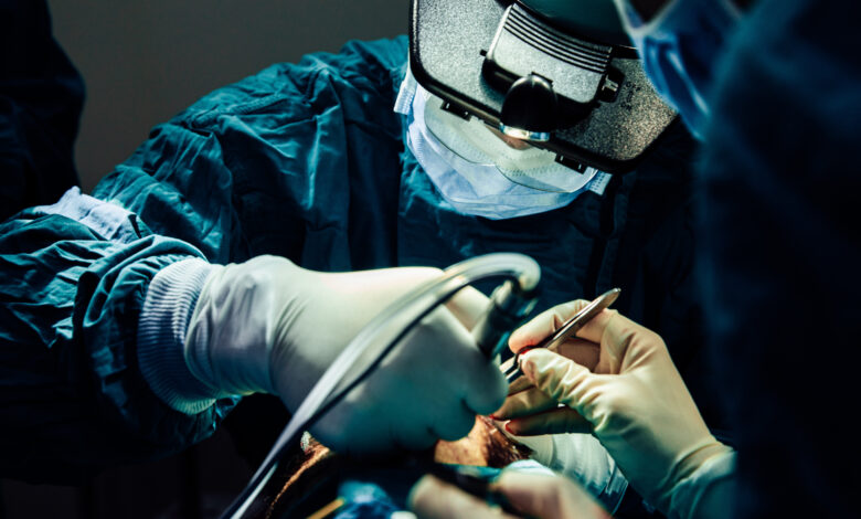 Close up doctor with surgical tools making surgery in the operating room, baldness treatment, hair transplant
